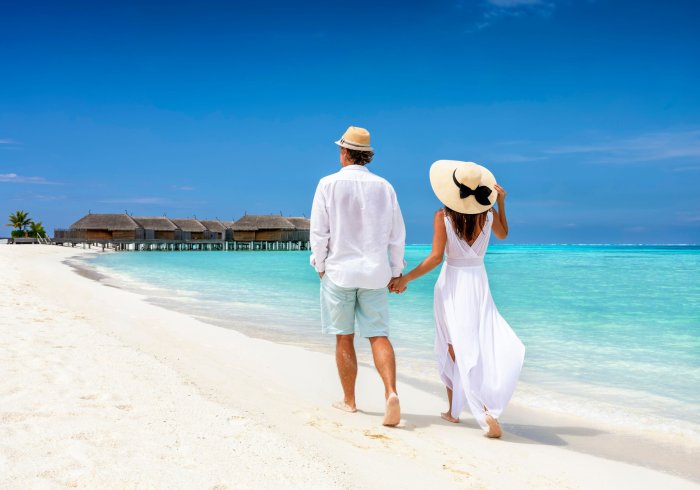Man and woman walk beach, honeymoon in Maldives.