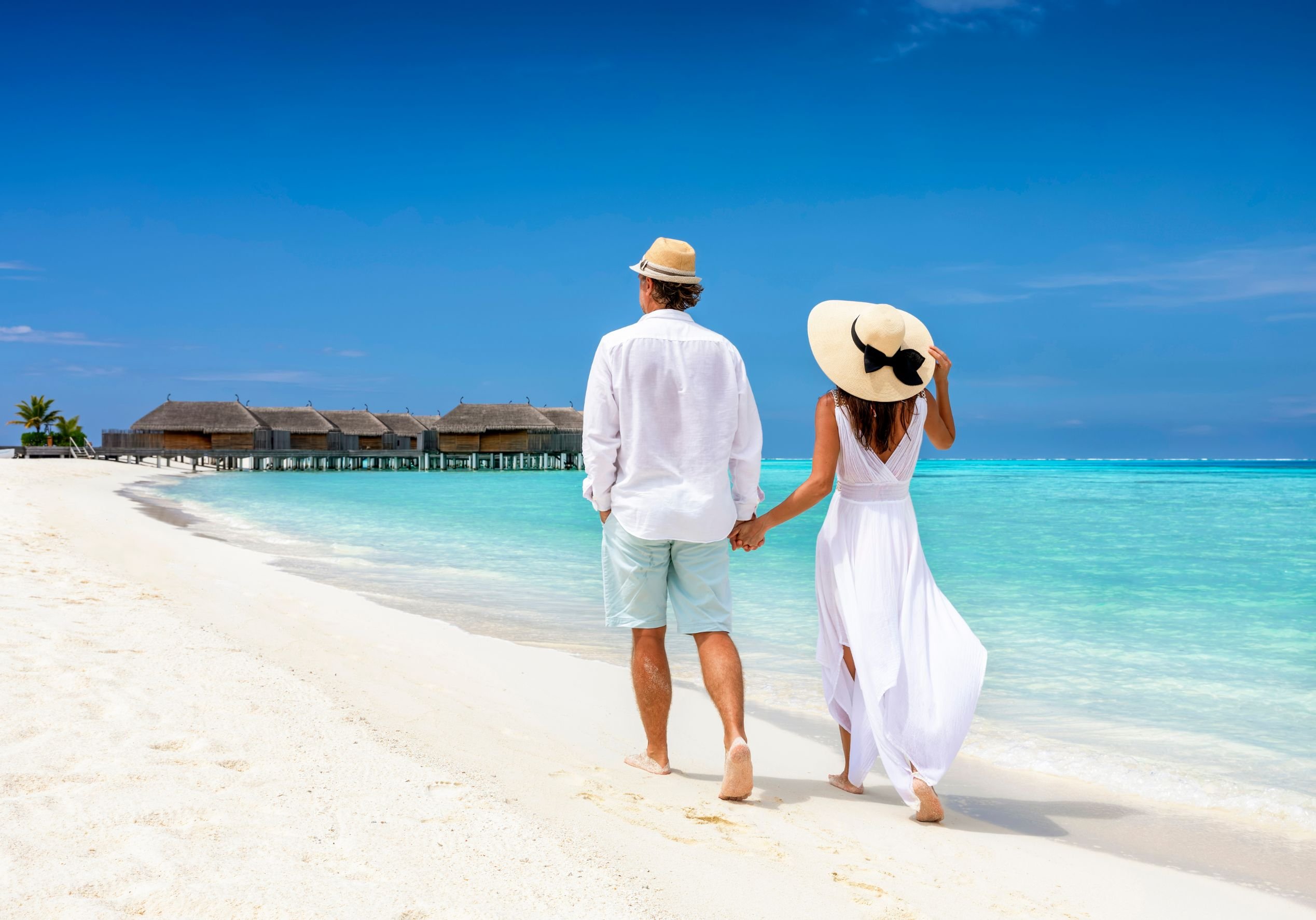 Man and woman walk beach, honeymoon in Maldives.
