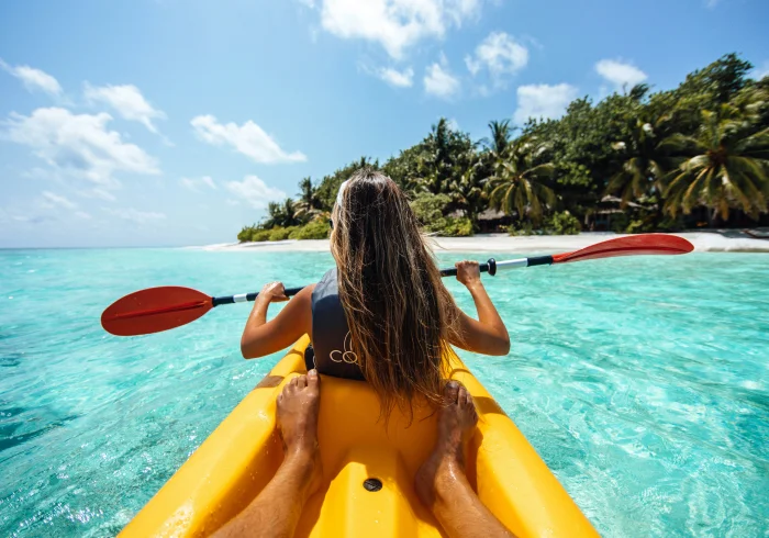 Woman kayak in clear water, Maldives tour, sun is out, nice blue sky.
