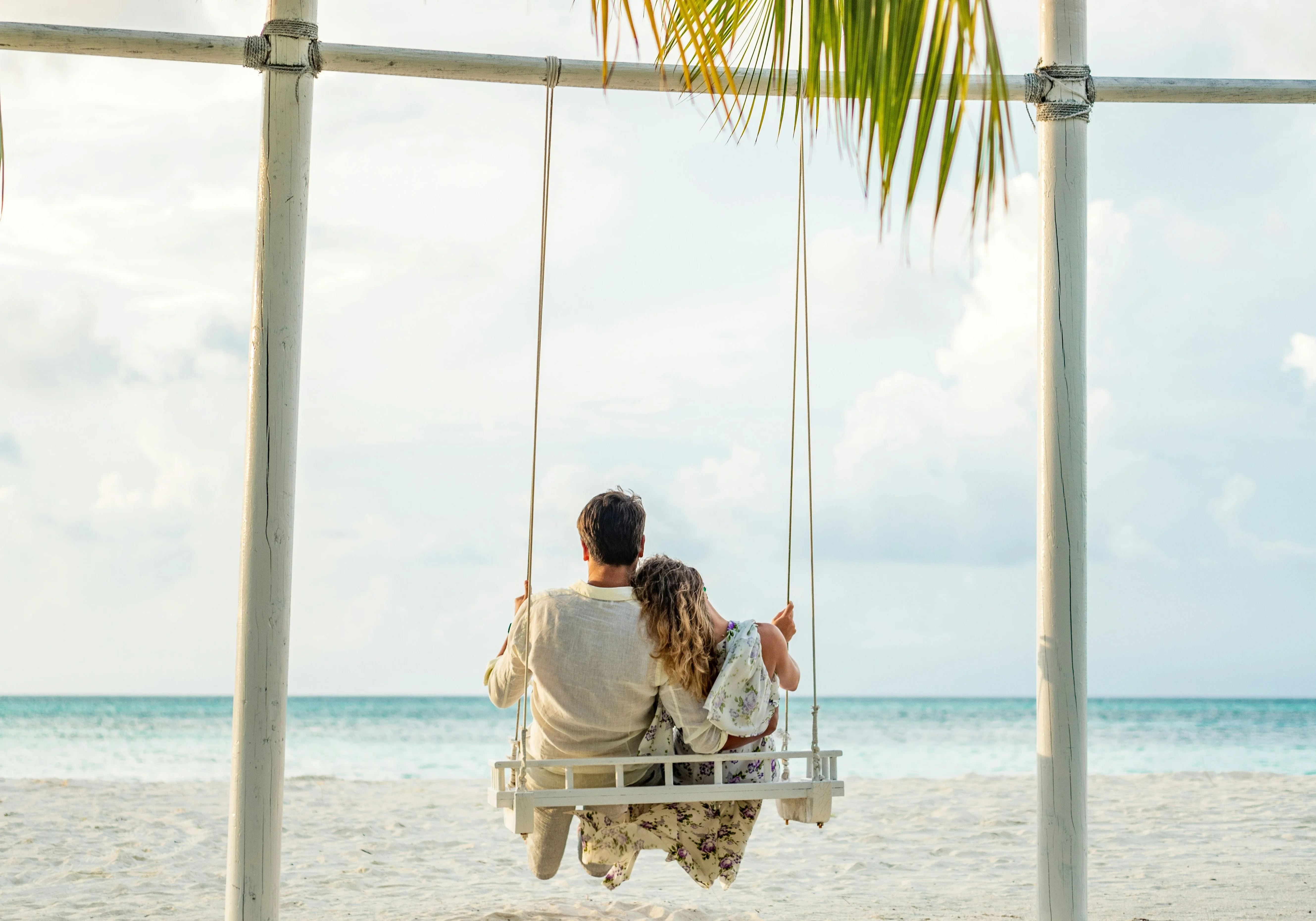 Romantic couple on beach swing with sea backdrop, perfect for a dream Maldives tour.