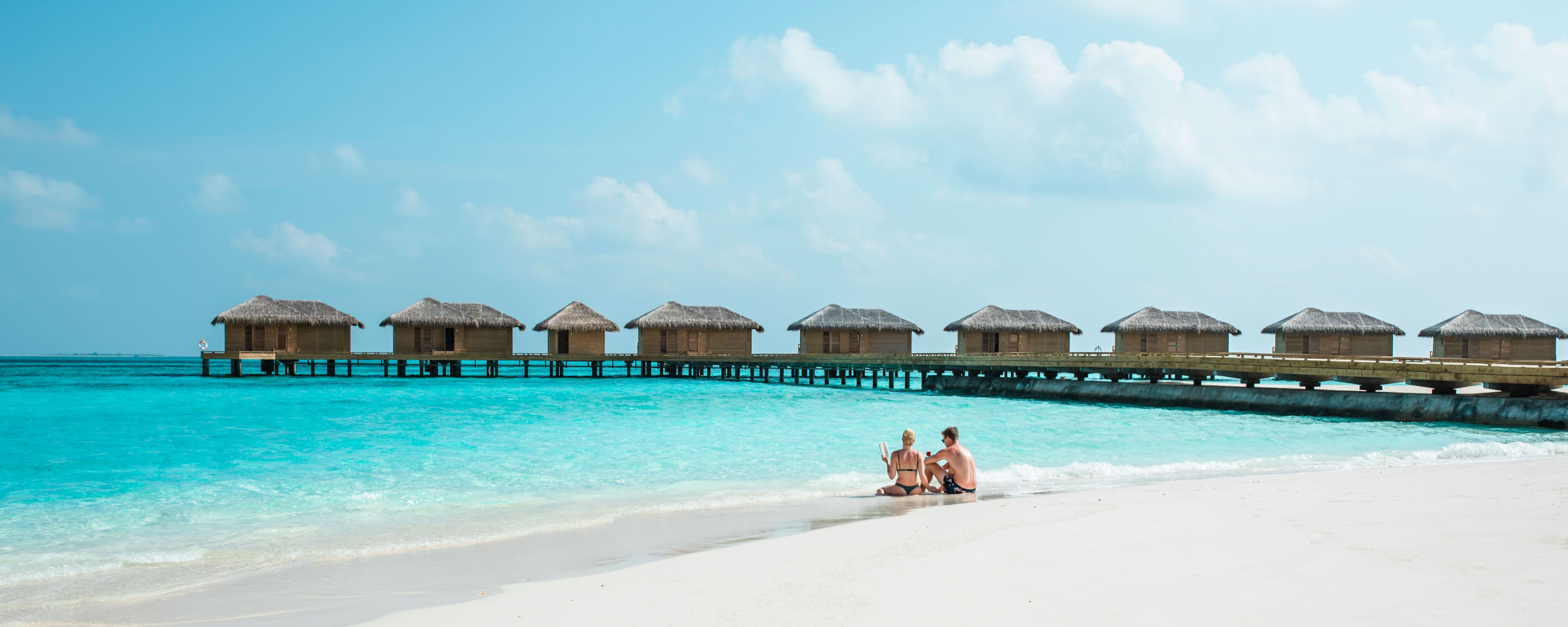 Maldives tour photo: Couple on beach with overwater bungalows.
