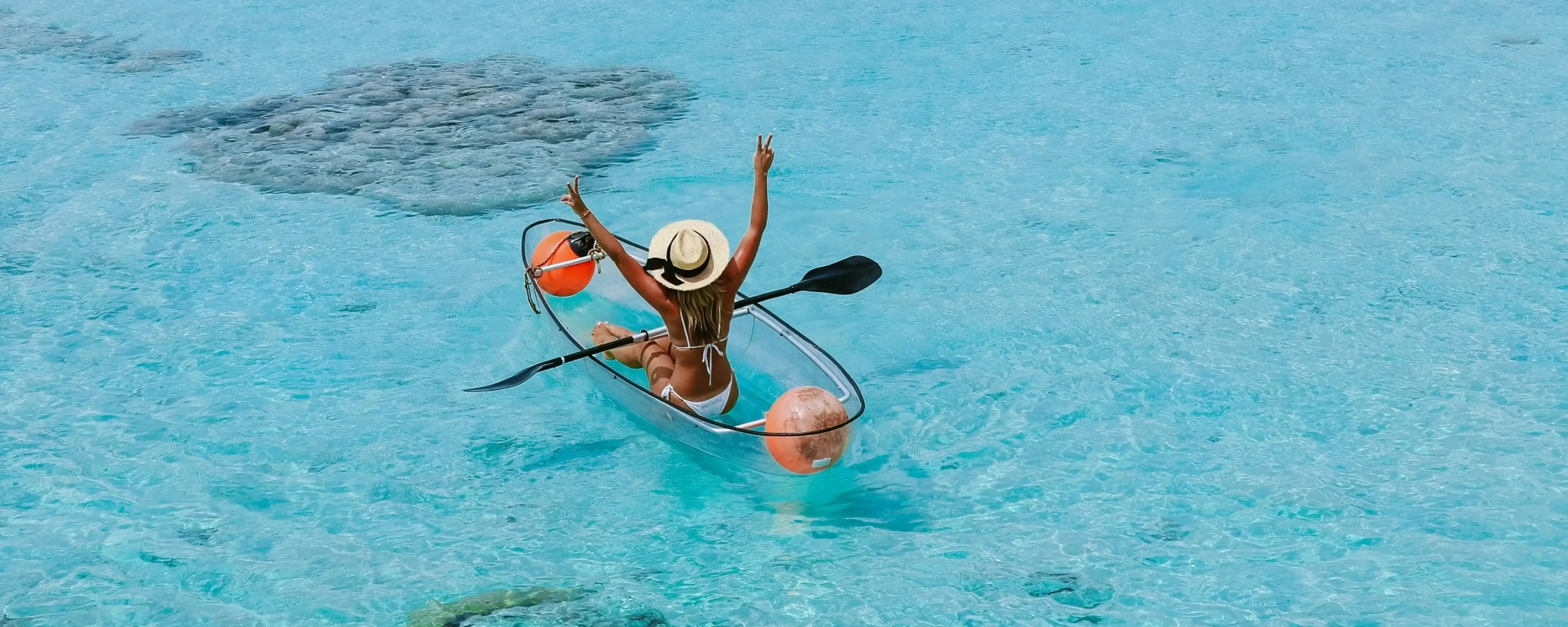 Beautiful view on a Maldives tour. See clear water, girl in a clear kayak, enjoying the sun.