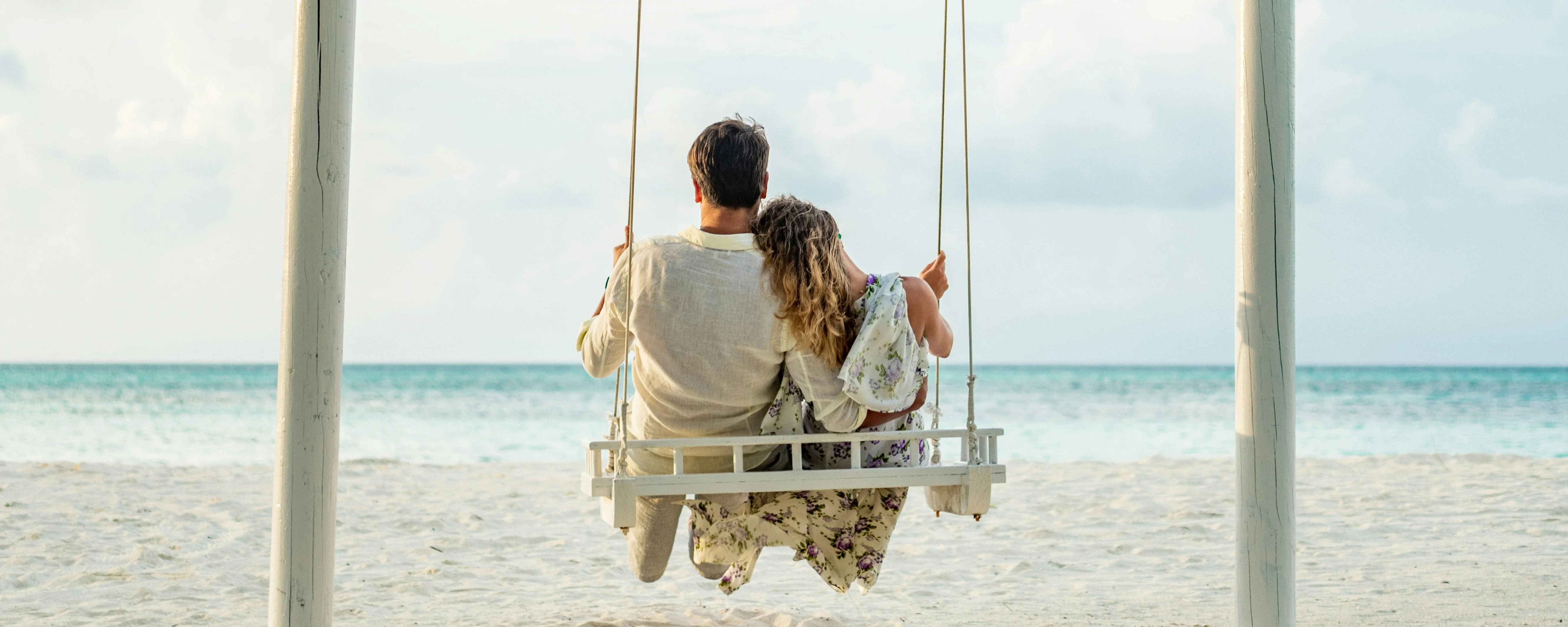 Romantic Maldives tour image: couple enjoying sunset on a beach swing by the ocean.