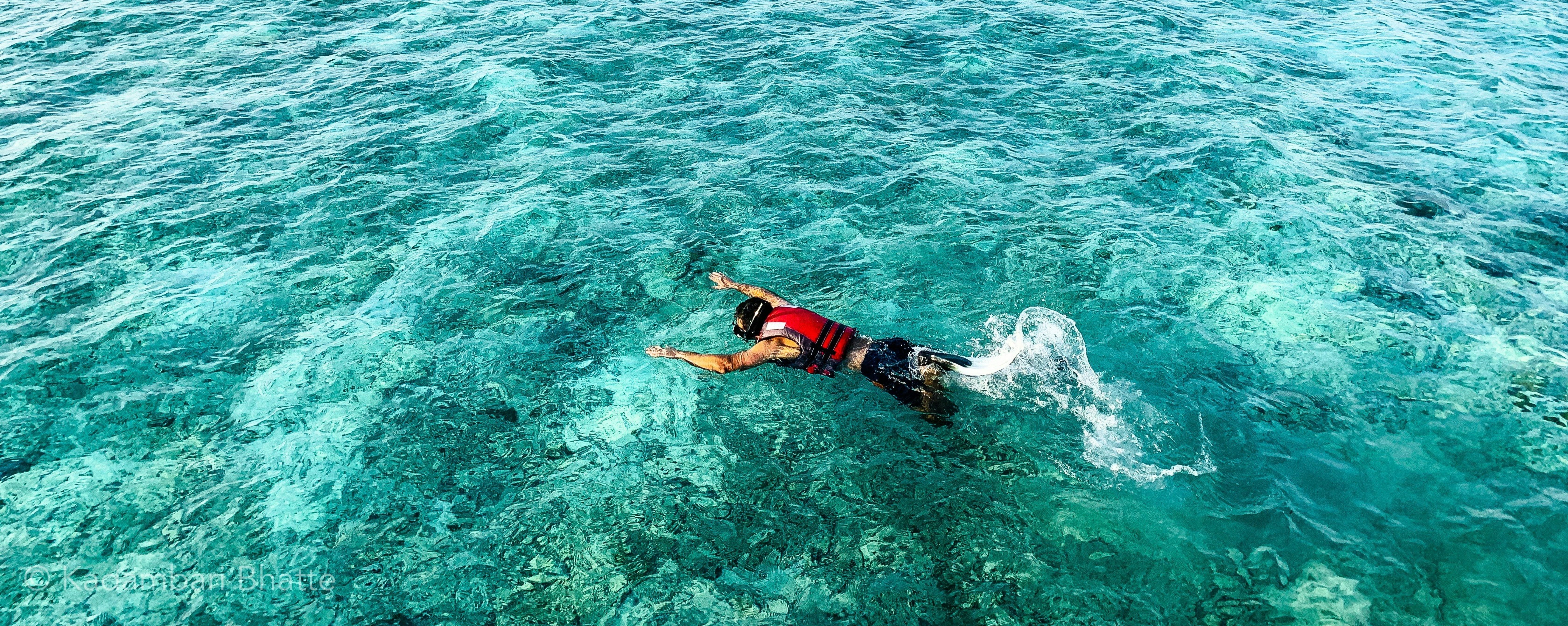 Man with snorkel mask swims in clear, blue water. Good for Maldives tour images. Enjoy the underwater beauty.