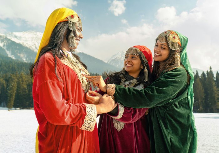 Smiling women in traditional Kashmiri Pheran dresses and Kasaba headwear. Experience local culture on your next Kashmir tour!